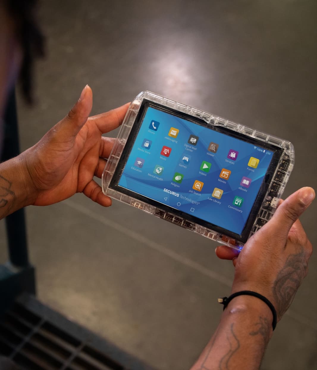 The image shows a person's hands holding a tablet device with a colorful display of various app icons.